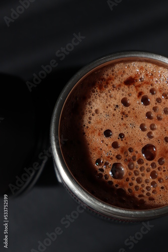 a thermo cup of cappuccino coffee on a black background © Diana Kozii