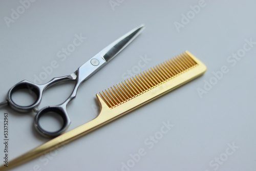 scissors and comb on white background.gold comb and silver scissors.silver scissors on white background.barber tools.hairdresser.gold scissors.