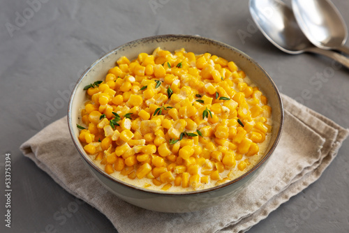 Homemade Slow Cooker Creamed Corn in a Bowl on a gray background, side view.