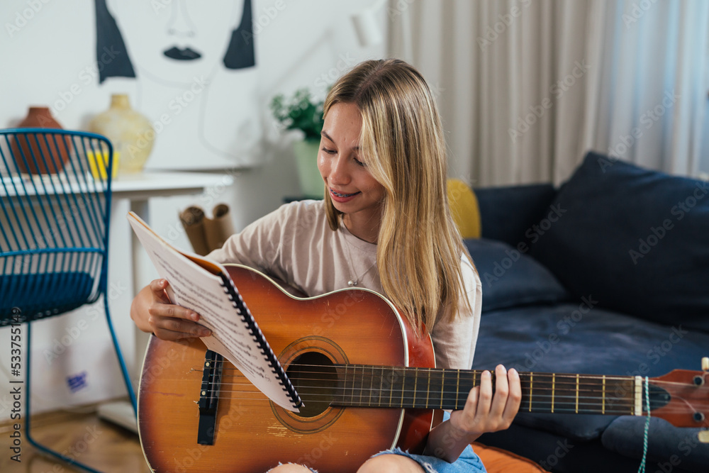 Fototapeta premium european teenager girl playing acoustic guitar at home