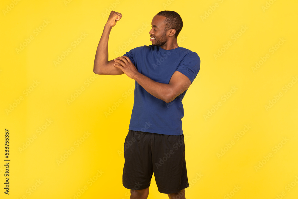 Fototapeta premium Sporty African American Guy Showing Biceps Muscles On Yellow Background
