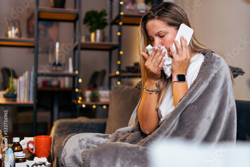 technology, health and cold concept - sad sick woman in blanket using smart phone at home