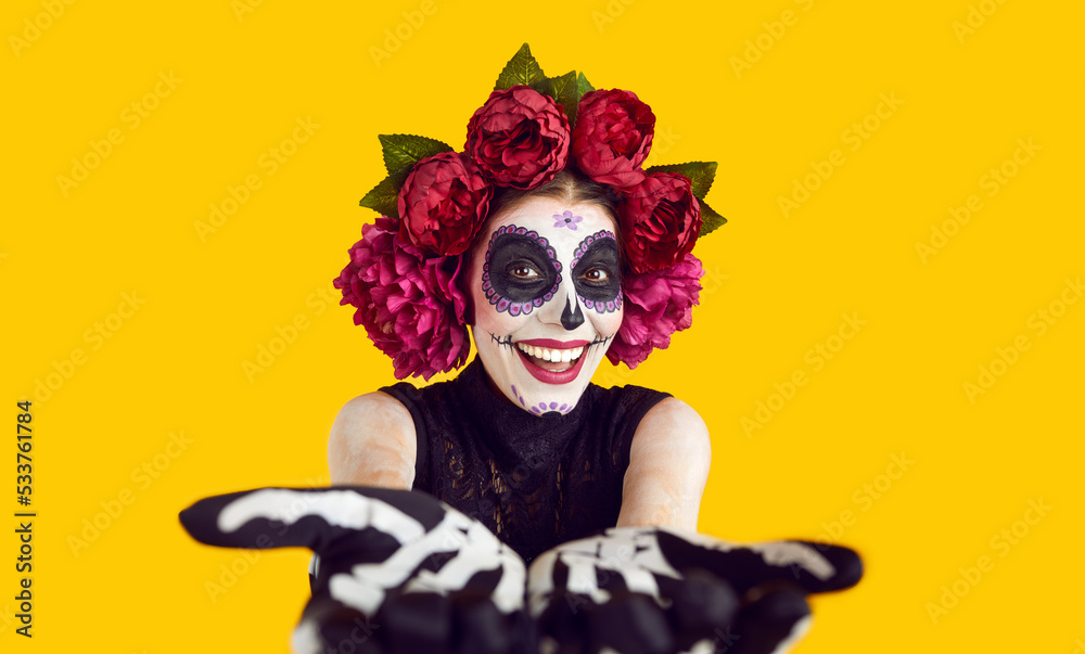 POV studio shot of happy smiling woman in spooky costume. Cheerful joyful fashion model lady with Catrina mask sugar skull makeup outstretching hands to camera. Halloween and Day of the Dead concept