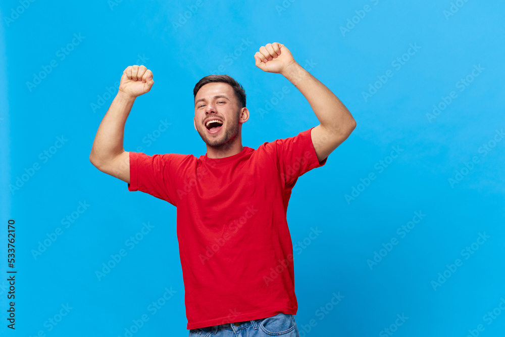 Overjoyed happy tanned handsome man in red t-shirt raise fist up have big win say Yeah posing isolated on blue studio background. Copy space Banner Mockup. People emotions Lifestyle concept Overjoyed happy tanned handsome man in red t-shirt raise fist up have big win say Yeah posing isolated on blue studio background. Copy space Banner Mockup. People emotions Lifestyle concept