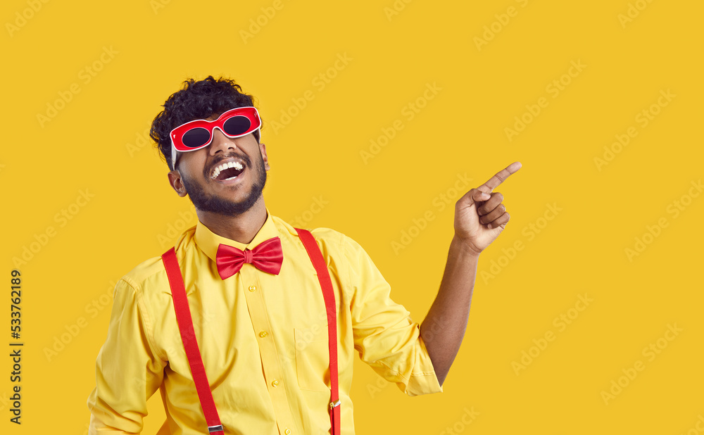 Funny extravagant Indian guy on orange background is advertising new  promotion or offering sale. Man in