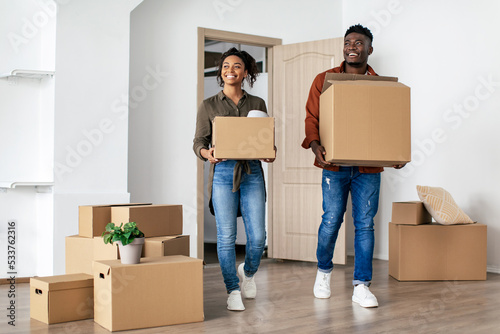 Cheerful African American Couple Carrying Moving Boxes Into New Home