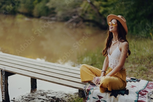 Schilderij op canvas Woman in hippie hat smiling and doing yoga meditating in the lotus position in t
