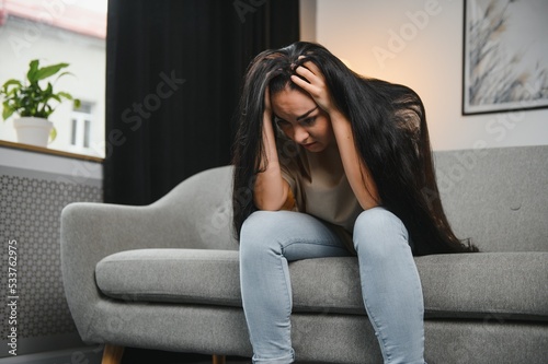 Depressed young woman on sofa at home. © Serhii
