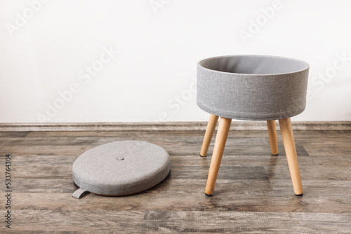 Trendy stool with and build-in storage. Side view, white wall, space photo