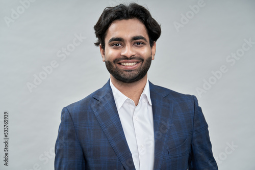 Photo Happy young indian business man ceo leader, arab professional manager, smiling expert businessman executive wearing suit looking at camera isolated on beige, close up headshot portrait