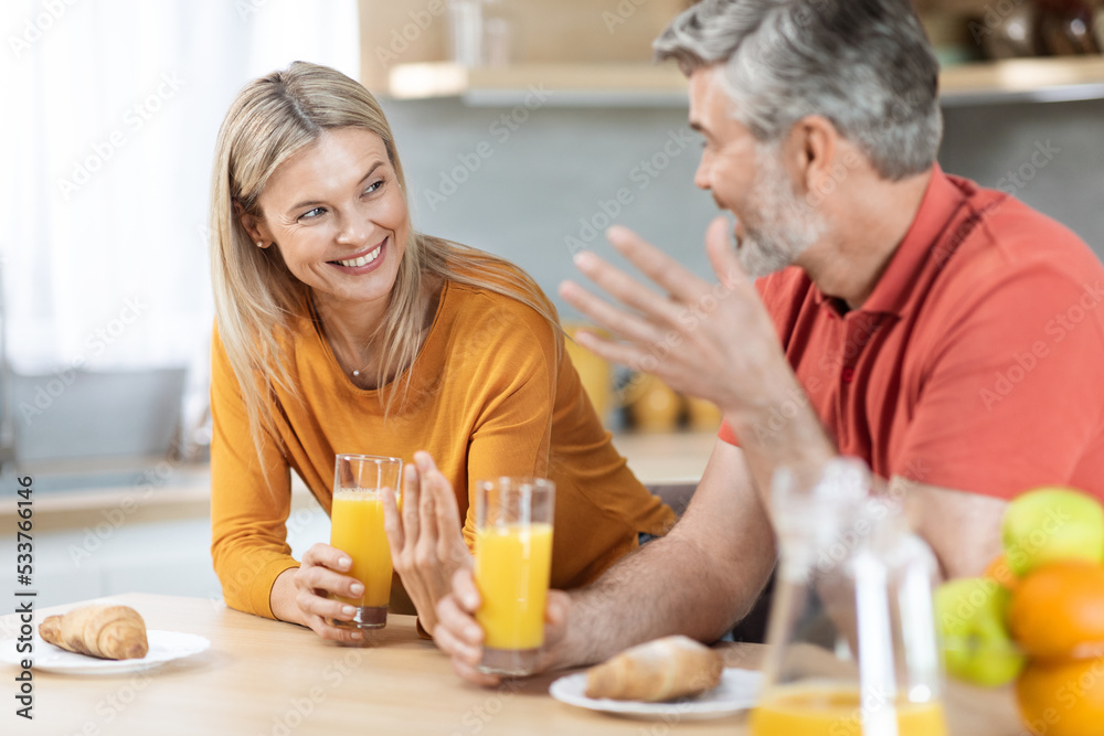 Happy loving spouses having conversation while eating at kitchen