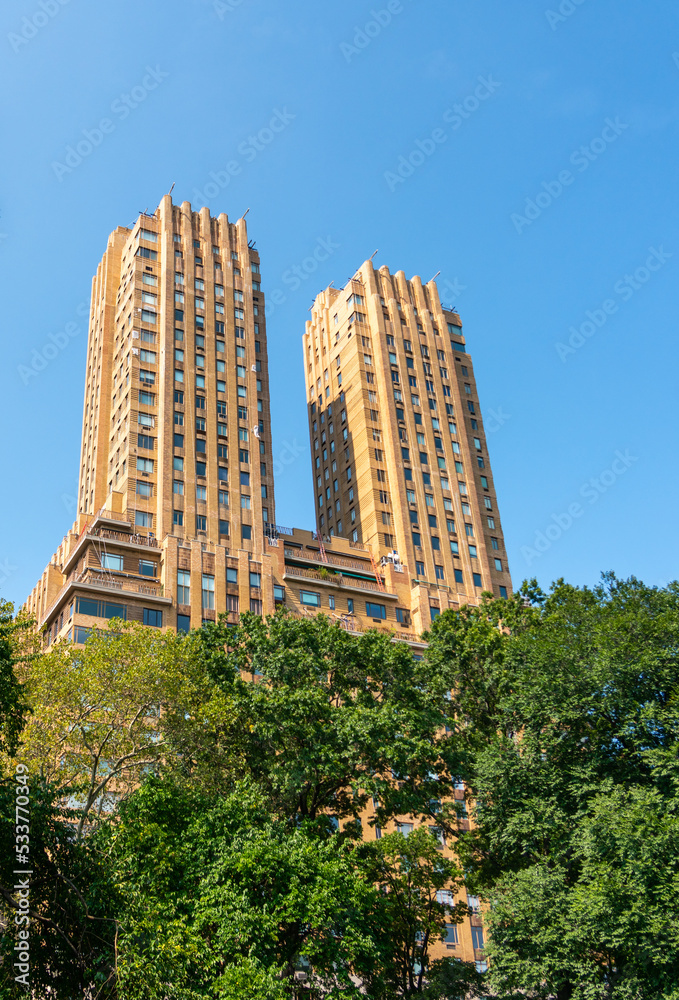 Obraz premium Towering towers of the Majestic apartments above the green trees of Manhattan's central park