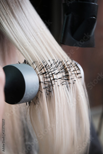 Young woman in a hairdressing salon dyes her hair blond and dries hair photo