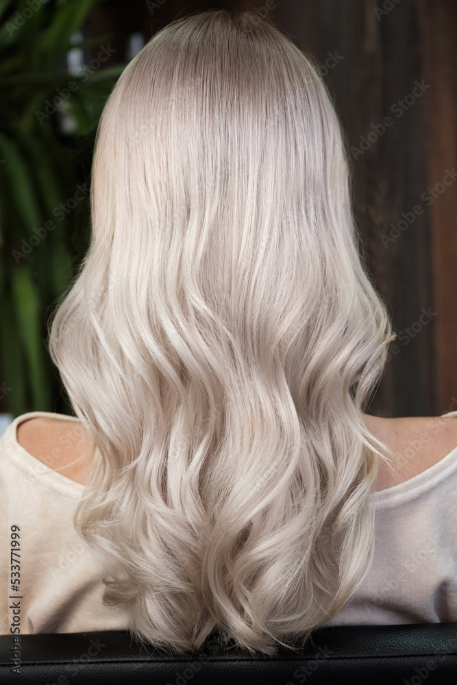 Naklejka premium Young woman in a hairdressing salon dyes her hair blond