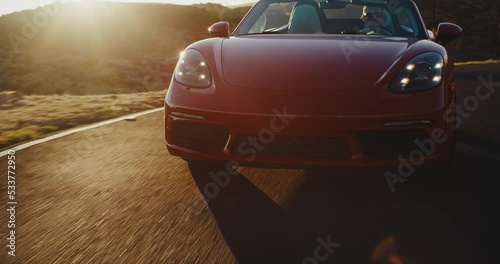 Epic sunset drive, red sports car driving on desert road at sunset