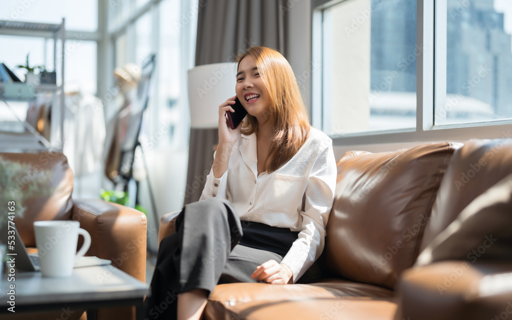 Asian woman on the phone talking on the sofa happily and smiling. Asian woman on the phone talking on the sofa happily and smiling.