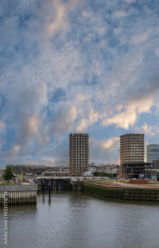 Antwerpen, Flanders, Belgium - July 10, 2022: Jattendijk lock entrance from Scheldt River. 2 of 5 modern condominium builidngs on Bataviastraat under sunrise blue cloudscape.