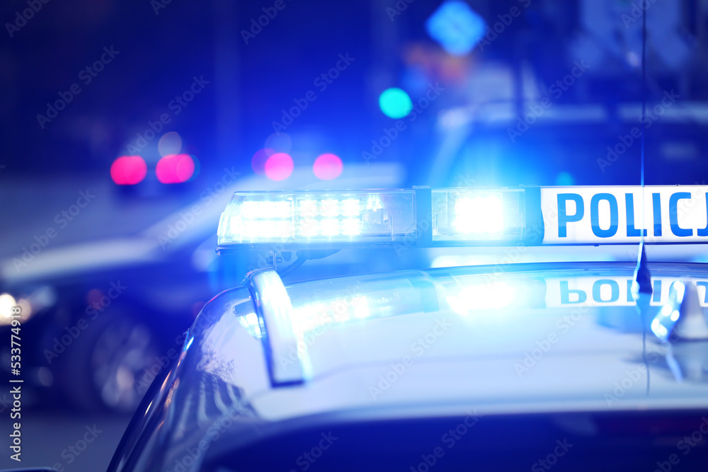 Radiowóz polska policja z  Sygnalizator błyskowy niebieski na dachu radiowozu.  Alarmowo wieczorem.  - obrazy, fototapety, plakaty 