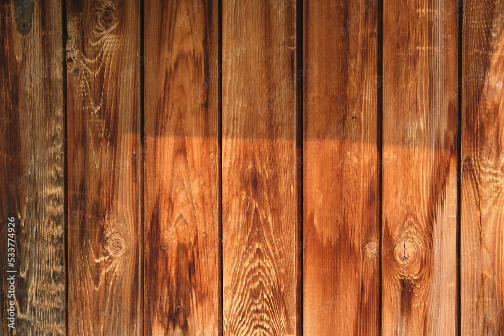 The texture of an old fence with a shadow. Wood texture with vertical lines. The texture of wood with knots and holes. The background of a fence damaged by time. The texture of an old fence with a shadow. Wood texture with vertical lines. The texture of wood with knots and holes. The background of a fence damaged by time.