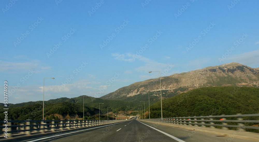 Empty straight road in the beautiful green nature and mountains. Highway in the middle of the mountains 