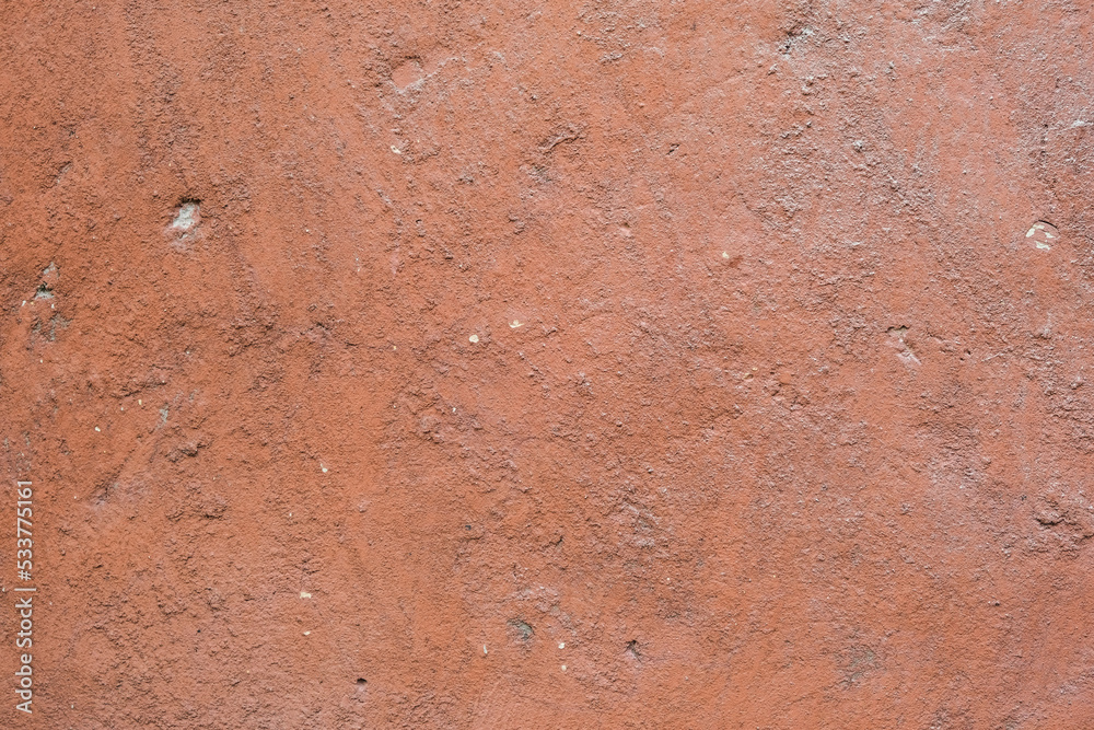 The texture of old painted concrete. The concrete background is dusty pink. The background of a painted wall with cracks. The texture of old painted concrete. The concrete background is dusty pink. The background of a painted wall with cracks.