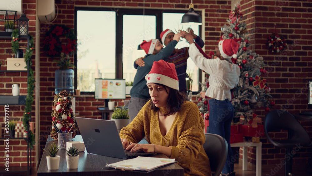 Stressed woman being disturbed by festive noise and colleagues celebrating christmas eve. Feeling frustrated and tired, interrupting work because of noisy people, xmas winter holiday season. Stressed woman being disturbed by festive noise and colleagues celebrating christmas eve. Feeling frustrated and tired, interrupting work because of noisy people, xmas winter holiday season.
