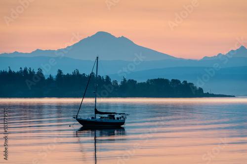 Colorful Sunrise Over Mt. Baker With a Sailboat in the Foreground.  Beautiful calm morning in the San Juan Islands as the majestic Mt. Baker looms in the background. photo