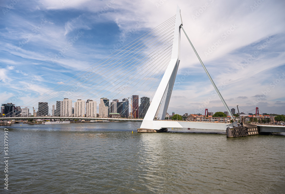 Rotterdam, Netherlands - July 11, 2022: Erasmusbrug, bridge. South base nicknamed The Swan under blue cloudscape. New high rise architecture on Boompjeskade other side of New Meuse river