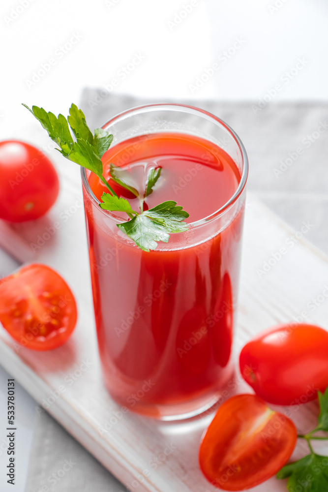Refreshing tomato juice with parsley on white background. Vegan vegetable smoothie. Refreshing tomato juice with parsley on white background. Vegan vegetable smoothie.
