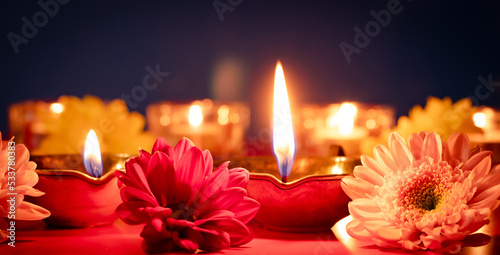 Happy Diwali. Traditional Indian festival of light. Burning diya oil lamps and flowers on red background. Banner format.
