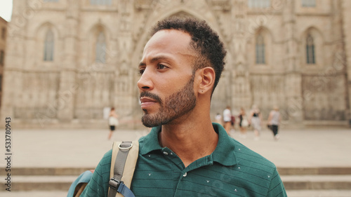 Photography Close-up of young tourist man with backpack on his shoulder, standing on the squ