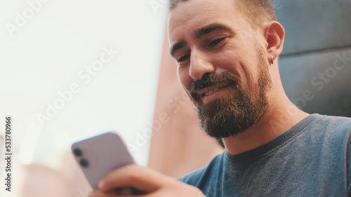 Young adult man with beard uses phone outside