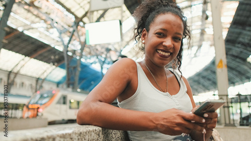 Φωτογραφία Young mixed race woman sitting at the railway station and looks at on camera, us