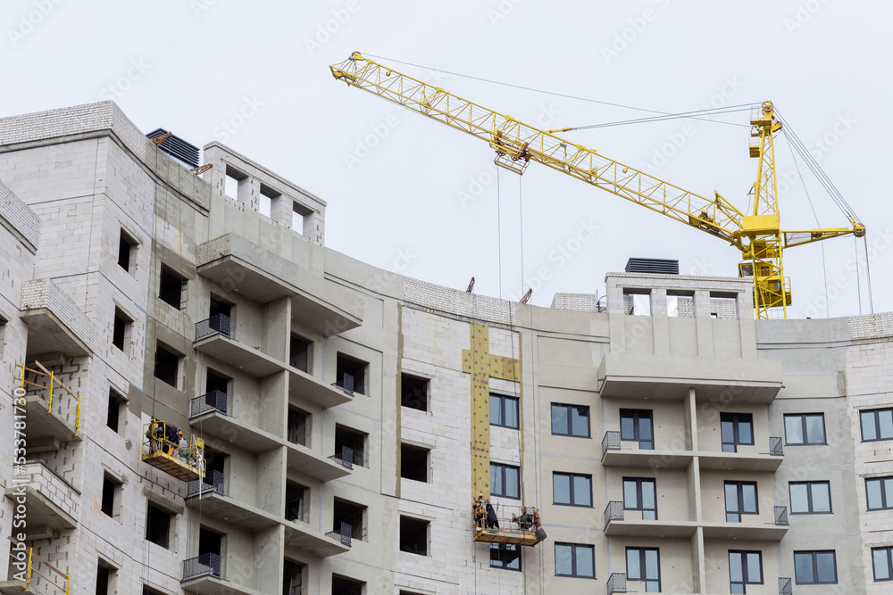 The process of insulating external walls in a multi-storey building under construction.