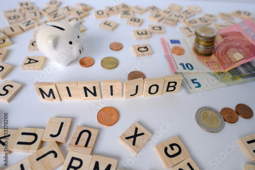 Fotografie paper euro banknotes, piggy bank, bills on table among euro coins, word Mini job