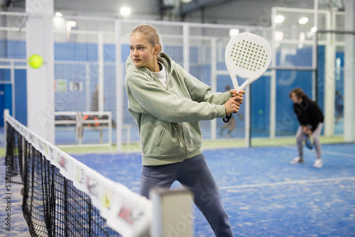 Padel game - teen girl actively kicks the ball during a padel game