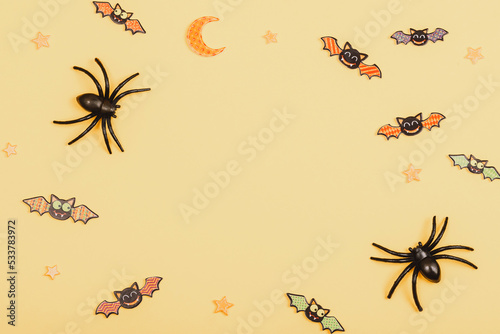 Halloween festive background with spiders and bats on yellow. Top view, flat lay, copy space