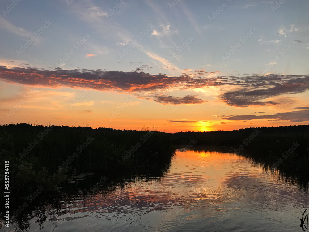 View of the sunset on the lake between the reeds, with blue skies and clouds. Tourism and travel concept.