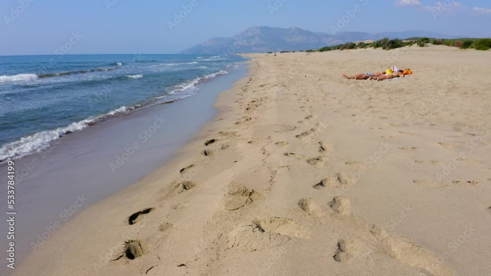 Tourists sunbathing on the beach. Calm sea waves washing the shore. Vacation and holiday concept. Tourists sunbathing on the beach. Calm sea waves washing the shore. Vacation and holiday concept.
