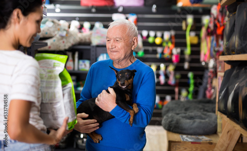 Woman helping an elderly man buy dry dog food