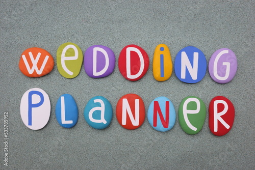 Wedding Planner, professional name composed with multi colored stone letters over green sand