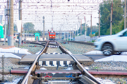 locomotive of Russian railways at station is approaching a railway crossing which dangerously crosses a passenger car