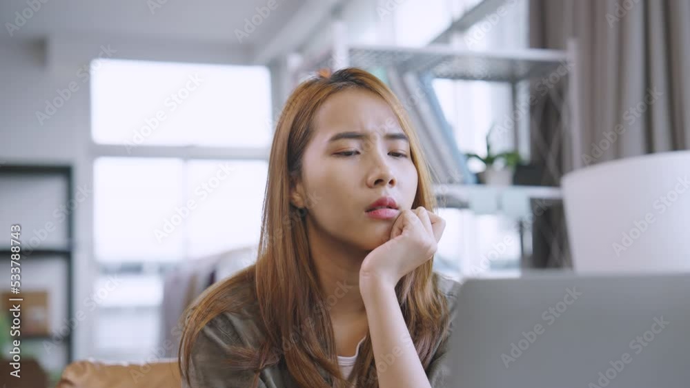 Young Asian woman working on laptop computer looking away thinking Young Asian woman working on laptop computer looking away thinking