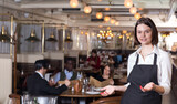 Portrait of smiling female waiter who is standing in luxurious restaurant.