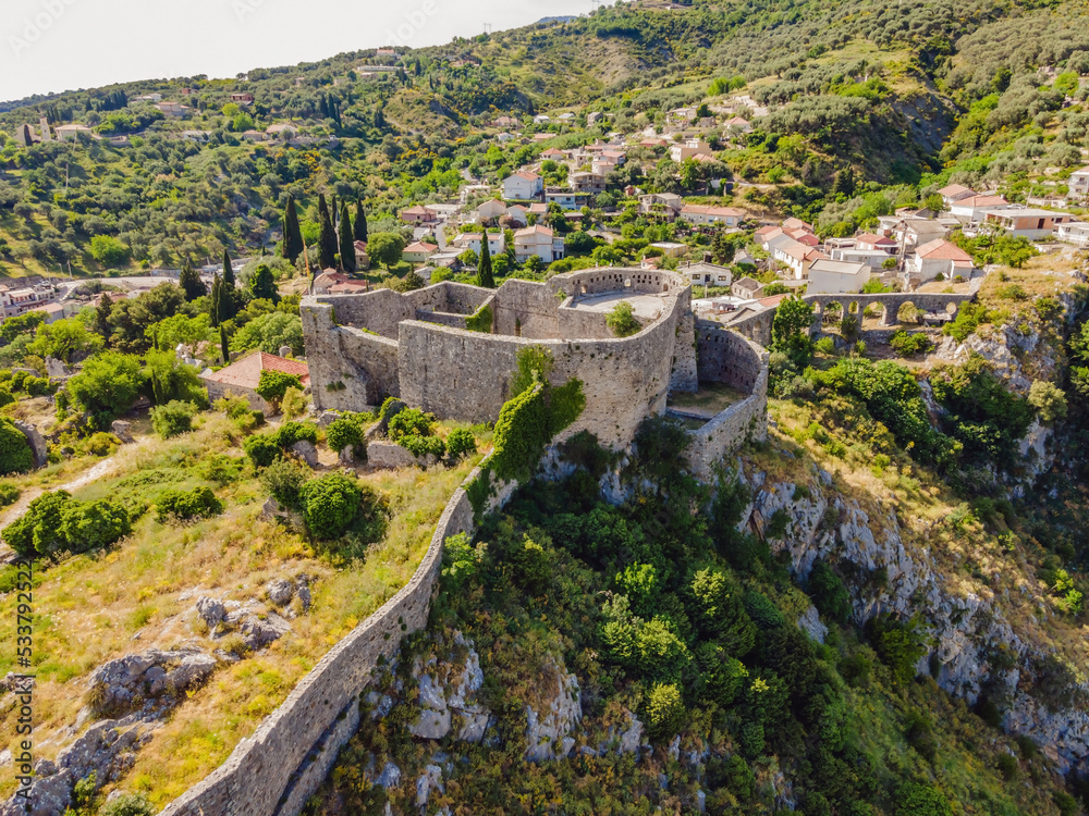 Old city. Sunny view of ruins of citadel in Stari Bar town near Bar city, Montenegro. Drone view Portrait of a disgruntled girl sitting at a cafe table