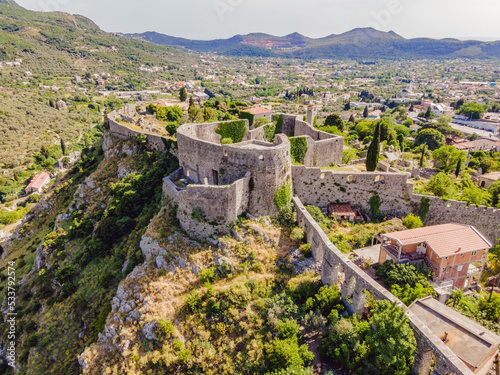 Old city. Sunny view of ruins of citadel in Stari Bar town near Bar city, Montenegro. Drone view Portrait of a disgruntled girl sitting at a cafe table photo