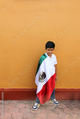 Latin Mexican boy of 8 years shows the flag of Mexico proud of his culture and tradition celebrates the national holidays of September 15 and Cinco de Mayo
