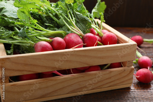 Crate with fresh ripe radish on wooden table, closeup