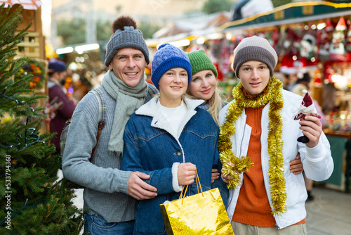 Cheerfull family with two teenagers posing with christmas gifts at Xmas market