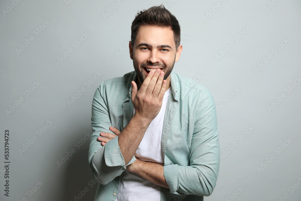 Young man laughing on light grey background. Funny joke Young man laughing on light grey background. Funny joke
